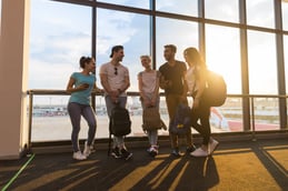 young-people-group-in-airport-lounge-near-windows-FY7S39V